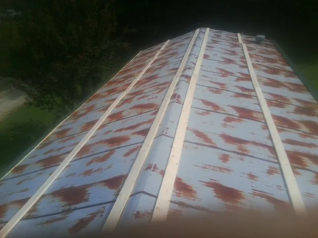 Rusted metal roof panels with new wood purlins before replacement in Buckingham